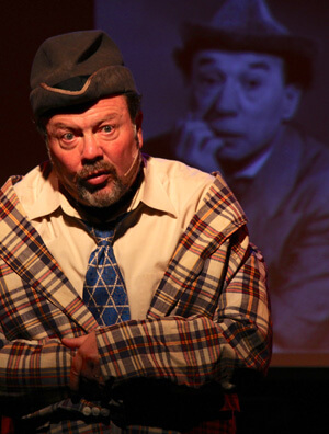 Avi Hoffman, standing in front of a picture of Menasha Skulnik, in “Still Jewish After All These Years,” at Stage 72 through October 23. | ANGELO FRABONI 
