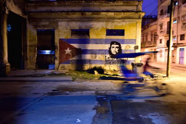 At dawn, a bicidriver passes a mural of Che Guevara on the Cuban flag. | DONNA ACETO